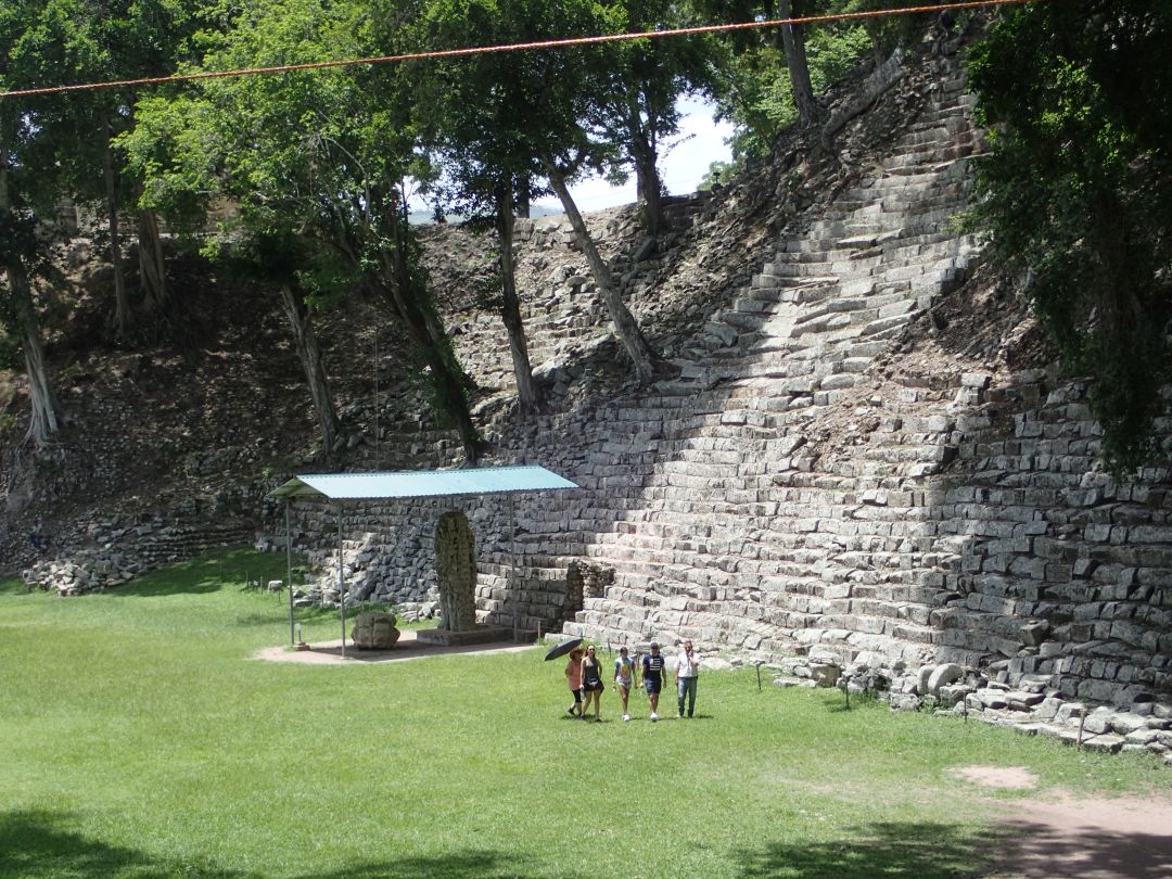 観光客の背後が巨大なピラミッド状建造物である神殿11の正面階段。その前に建立された石碑Nと祭壇（保護のため屋根がかけられている）